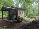 Backyard outdoor kitchen with built-in grill, counter space, and picnic tables in a wooded area at 4008 Old Nc 86, Hillsborough, NC 27278