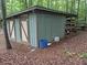 Outdoor storage building with double doors and covered shelving area in wooded backyard at 4008 Old Nc 86, Hillsborough, NC 27278