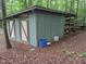 Outdoor storage building with double doors and covered shelving area in wooded backyard at 4008 Old Nc 86, Hillsborough, NC 27278