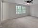 Bedroom with neutral carpet, ceiling fan, and two windows overlooking a green lawn at 403 Carpenter Fletcher Rd, Durham, NC 27713