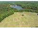 Scenic aerial view capturing the expansive field and a lake surrounded by lush greenery at 404 Blooming Meadows Rd, Holly Springs, NC 27540