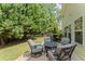 Backyard patio boasts an outdoor seating area amidst lush trees, ideal for relaxing and lounging at 404 Blooming Meadows Rd, Holly Springs, NC 27540
