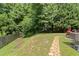 Landscaped backyard featuring a stone pathway and lush greenery, perfect for outdoor entertaining at 404 Blooming Meadows Rd, Holly Springs, NC 27540