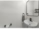 Modern half bathroom featuring a pedestal sink, sleek black fixtures, and contemporary mirror at 404 Blooming Meadows Rd, Holly Springs, NC 27540