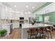 Modern kitchen with white cabinets, stainless steel appliances, and quartz island with bar seating at 404 Blooming Meadows Rd, Holly Springs, NC 27540