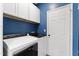 Laundry area features white washer, dryer, storage cabinets, and blue walls at 404 Blooming Meadows Rd, Holly Springs, NC 27540