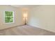 Bedroom with neutral walls and carpet featuring a large window and corner lamp at 418 Byrams Ford Dr, Cary, NC 27513