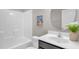 Bright bathroom featuring a tub with shower, single sink vanity, and decorative coastal-themed artwork at 517 Eagles Way, Mebane, NC 27302