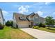 Two story home featuring a two-car garage, well-maintained lawn, and stone accents at the base at 517 Eagles Way, Mebane, NC 27302