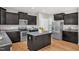 Well-lit kitchen featuring dark cabinets, stainless steel appliances, an island, and granite countertops at 517 Eagles Way, Mebane, NC 27302