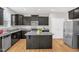 This open kitchen features dark cabinetry, an island, stainless appliances, and granite countertops at 517 Eagles Way, Mebane, NC 27302