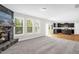 Open-concept living room featuring a stone fireplace, lots of windows, and an adjacent kitchen at 517 Eagles Way, Mebane, NC 27302