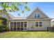 View of the home's rear exterior featuring a screened porch, green lawn, and traditional beige siding at 5216 Marcella Ct, Durham, NC 27707