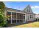 View of the home's rear exterior featuring a screened porch with outdoor seating and traditional beige siding at 5216 Marcella Ct, Durham, NC 27707