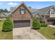 Stone-accented home featuring a two-car garage, manicured lawn, and tidy landscaping enhancing curb appeal at 5216 Marcella Ct, Durham, NC 27707
