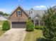 Exterior view of stone front home with a two-car garage, blue sky, and well-maintained landscaping at 5216 Marcella Ct, Durham, NC 27707