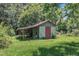 A utilitarian shed with a red door, offering ample storage in a verdant, tree-lined yard at 64 Doughty Ln # E, Middlesex, NC 27557