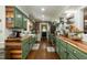 Spacious kitchen boasts wood counters, green cabinets, stainless appliances, brick accent wall, and white subway tile at 7216 Rabbit Run, Wake Forest, NC 27587