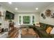 Bright living room featuring a large window, green sofa, and stylish decor, perfect for relaxing at 7216 Rabbit Run, Wake Forest, NC 27587