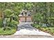 Long driveway leading to a brick home with a two-car garage surrounded by lush greenery and mature trees at 81106 Alexander, Chapel Hill, NC 27517