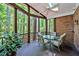 Screened-in back patio with glass table, cushioned chairs, ceiling fan, and wooded views at 81106 Alexander, Chapel Hill, NC 27517