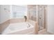 Bright bathroom features a garden tub and a separate glass enclosed shower at 835 New Derby Ln, Apex, NC 27523