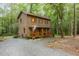 Two-story home with wood siding and a covered front porch surrounded by trees and a gravel driveway at 1012 King Cir, Chapel Hill, NC 27516
