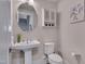 Stylish half-bath featuring a pedestal sink, decorative mirror, and modern fixtures at 10330 Sablewood Dr # 104, Raleigh, NC 27617