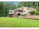 Spacious backyard featuring a charming yellow home with a covered porch and a multi-tiered deck surrounded by lush greenery at 106 Autumn Cir, Cary, NC 27518