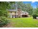 Expansive backyard view of a yellow home featuring a brick chimney, lush greenery, and a covered deck for outdoor relaxation at 106 Autumn Cir, Cary, NC 27518