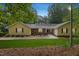 Charming single-story home with yellow siding and a stone facade, complemented by a well-manicured lawn and mature trees at 106 Autumn Cir, Cary, NC 27518
