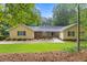 Inviting yellow home featuring a stone facade, well-manicured lawn and mature landscaping at 106 Autumn Cir, Cary, NC 27518