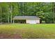 Detached garage with an adjacent carport, surrounded by a lush green lawn and mature trees at 106 Autumn Cir, Cary, NC 27518