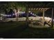 Cozy backyard with a stone fire pit, pergola, and string lights, perfect for outdoor evenings at 108 Holly Glen Ct, Holly Springs, NC 27540