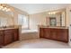 Bathroom featuring dual sinks with granite countertops, soaking tub, tile floors, and warm lighting at 108 Holly Glen Ct, Holly Springs, NC 27540