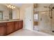Bathroom featuring a glass-enclosed shower, tile floors, granite countertop, and warm wood vanity at 108 Holly Glen Ct, Holly Springs, NC 27540