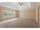 Spacious bedroom with tray ceiling, ceiling fan, neutral walls and carpet, and multiple windows at 108 Holly Glen Ct, Holly Springs, NC 27540