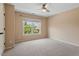 Bedroom with neutral walls and carpet, featuring a ceiling fan and large windows overlooking greenery at 108 Holly Glen Ct, Holly Springs, NC 27540