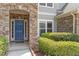 Inviting front entrance with a blue door, stone surround, and lush landscaping creating a welcoming curb appeal at 108 Holly Glen Ct, Holly Springs, NC 27540
