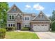 Beautiful two-story home featuring a stone and gray siding exterior and well-manicured lawn at 108 Holly Glen Ct, Holly Springs, NC 27540