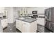 Bright kitchen with white cabinets, black countertops, an island with a sink, and stainless-steel appliances at 109 Murdock Creek Ct, Cary, NC 27519
