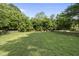 Lush, green backyard surrounded by mature trees and a classic wooden fence at 1133 Heritage Greens Dr, Wake Forest, NC 27587