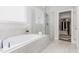 Bright bathroom featuring a large tub, glass-enclosed shower, and a walk-in closet at 119 Florentino Ct, Clayton, NC 27527