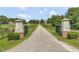 View of the private estate entrance with stone pillars and a long driveway leading to the main home at 119 Florentino Ct, Clayton, NC 27527