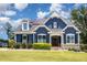 Charming two-story home featuring a blue exterior, stone accents, a well-manicured lawn, and solar panels at 119 Florentino Ct, Clayton, NC 27527