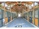 Spacious horse barn interior features wooden stalls and well-lit aisle, providing a comfortable environment for horses at 119 Florentino Ct, Clayton, NC 27527