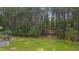 A view of the lush green yard featuring a deck, mature trees, and the serene wooded perimeter at 1210 Bayview Ct, Franklinton, NC 27525