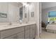Well-lit bathroom with double sinks, gray vanity, and a view into the connected bedroom at 1217 Clandon Square Rd, Hillsborough, NC 27278