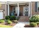Inviting front porch with white pillars, decorative wreath on the front door, and lush landscaping at 1217 Clandon Square Rd, Hillsborough, NC 27278