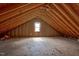 An attic space with exposed beams and a window, showcasing the potential for storage or expansion at 1230 Sykes Rd, Spring Hope, NC 27882